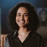 Portrait of a smiling woman with curly hair standing in a church setting with an altar.